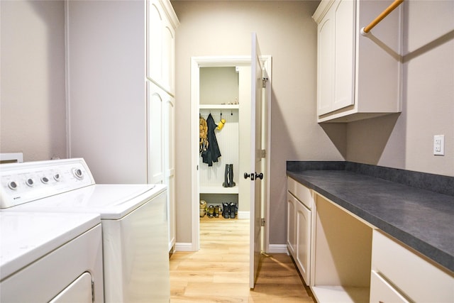 clothes washing area with light wood-type flooring, washing machine and clothes dryer, cabinet space, and baseboards