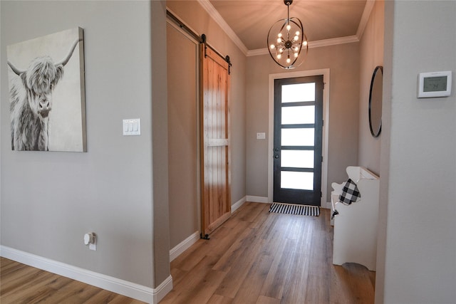 foyer featuring crown molding, wood-type flooring, a barn door, and a chandelier