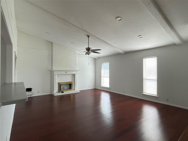 unfurnished living room with ceiling fan, lofted ceiling with beams, dark hardwood / wood-style floors, and a brick fireplace