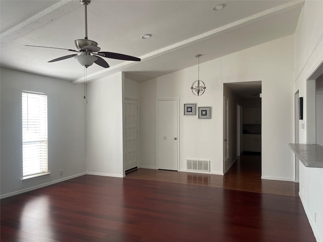 empty room featuring dark hardwood / wood-style floors, plenty of natural light, ceiling fan with notable chandelier, and vaulted ceiling