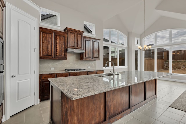 kitchen with tasteful backsplash, sink, pendant lighting, an inviting chandelier, and lofted ceiling