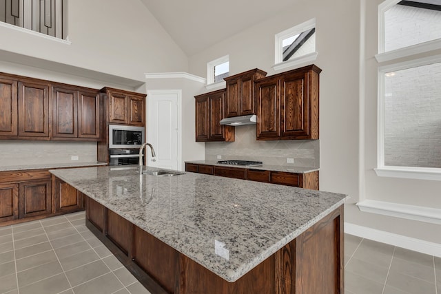 kitchen with decorative backsplash, sink, an island with sink, and stainless steel appliances