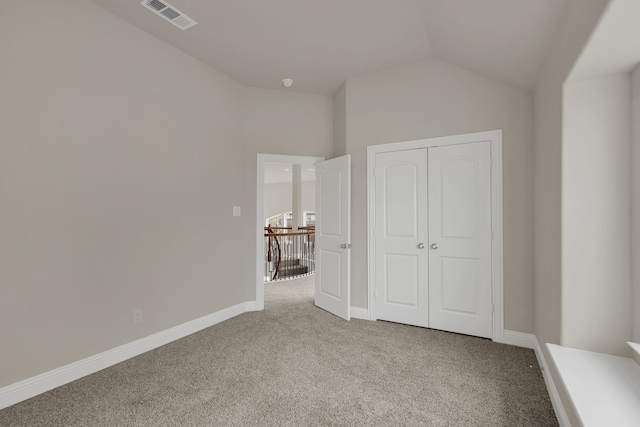 unfurnished bedroom featuring light colored carpet, a closet, and lofted ceiling