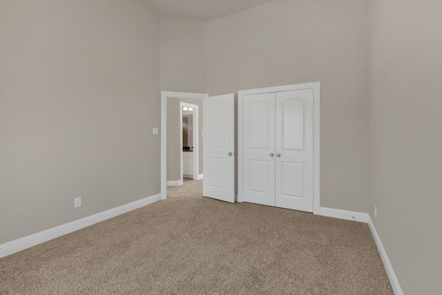 unfurnished bedroom featuring carpet floors, a high ceiling, and a closet