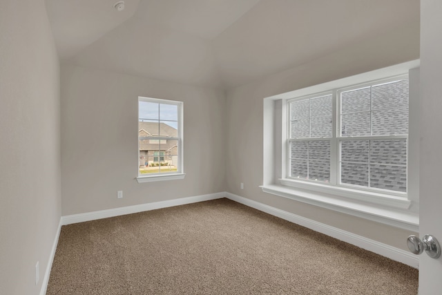 carpeted empty room featuring vaulted ceiling