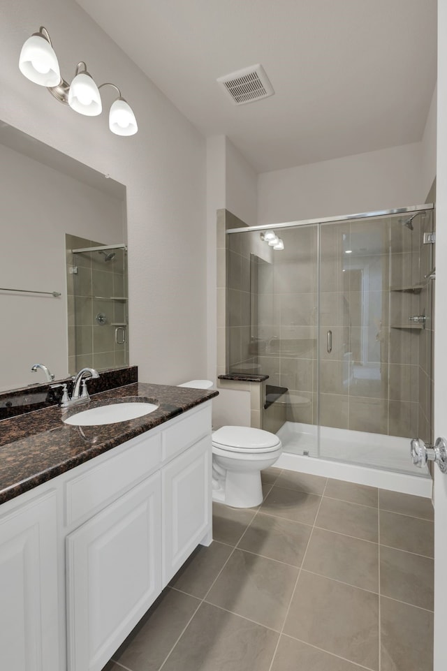 bathroom with tile patterned flooring, vanity, toilet, and walk in shower