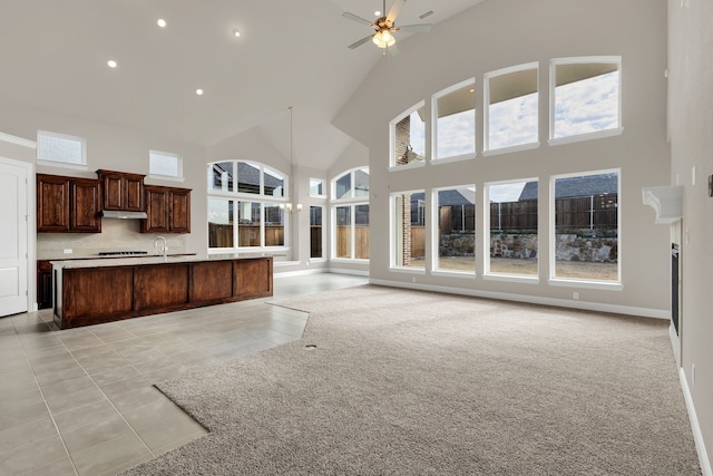 kitchen featuring decorative backsplash, ceiling fan, a kitchen island with sink, and a high ceiling