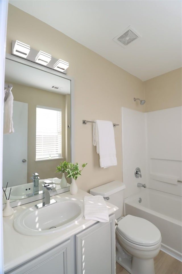 full bathroom featuring hardwood / wood-style flooring, vanity, shower / bathtub combination, and toilet