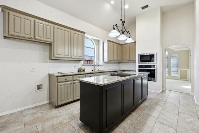 kitchen with sink, light stone counters, a kitchen island, built in microwave, and oven