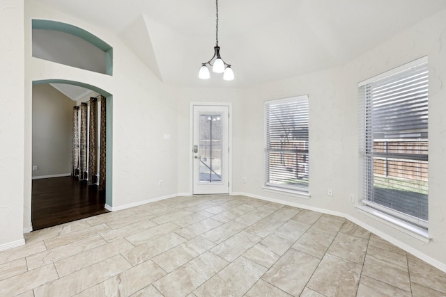 empty room featuring lofted ceiling and a chandelier