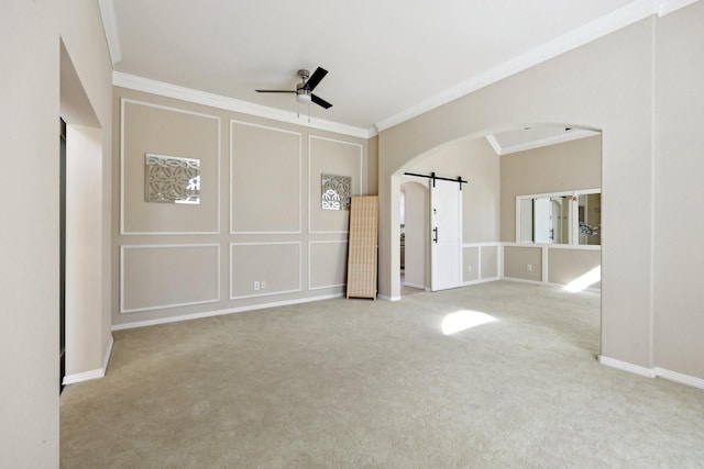 unfurnished room with ceiling fan, ornamental molding, a barn door, and light carpet