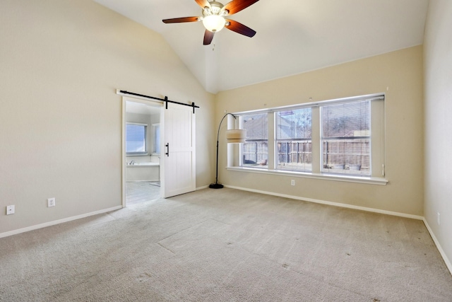 spare room with lofted ceiling, light carpet, a barn door, and ceiling fan