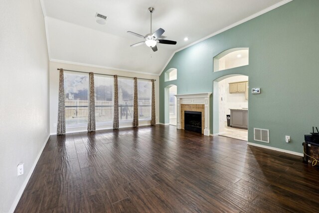 unfurnished living room featuring ceiling fan, hardwood / wood-style floors, a fireplace, ornamental molding, and vaulted ceiling