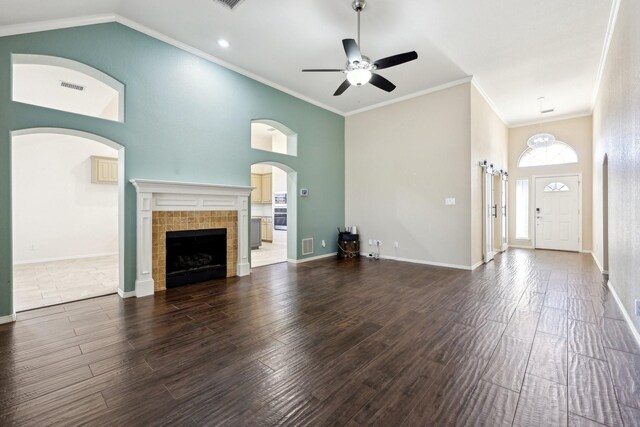 unfurnished living room featuring a tile fireplace, crown molding, and dark hardwood / wood-style flooring