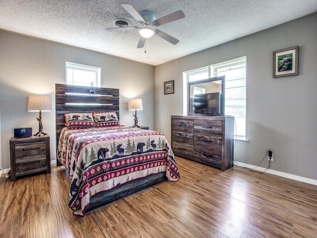 bedroom with hardwood / wood-style flooring, ceiling fan, and a textured ceiling