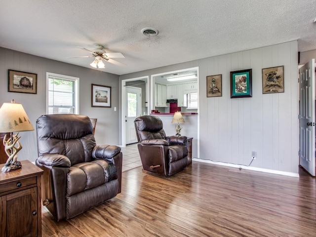 living room featuring ceiling fan, hardwood / wood-style floors, and a textured ceiling