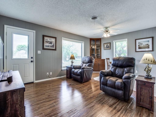 living room with ceiling fan, a textured ceiling, and dark hardwood / wood-style flooring