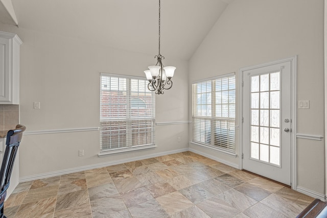 unfurnished dining area with a wealth of natural light, high vaulted ceiling, and a notable chandelier