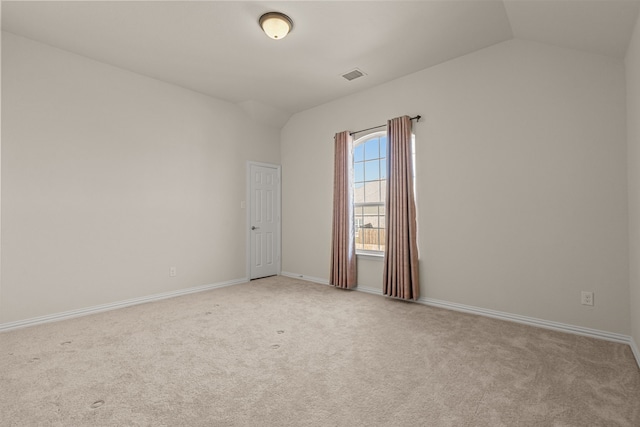 carpeted spare room with vaulted ceiling