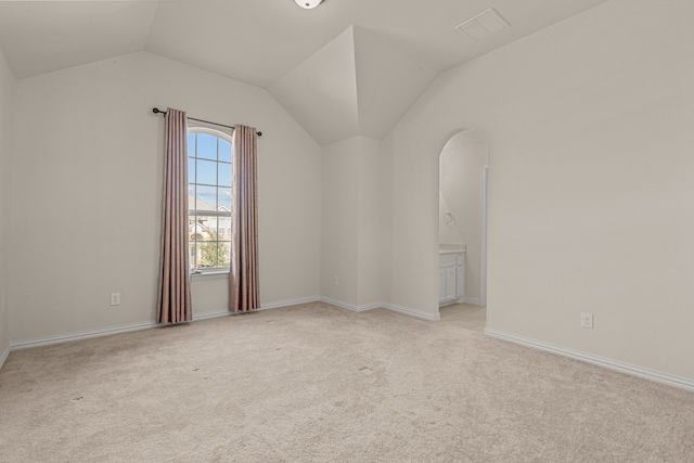 carpeted spare room with vaulted ceiling