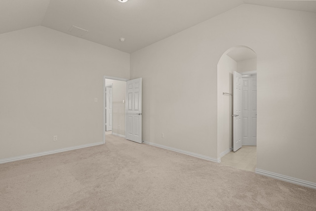 carpeted empty room with vaulted ceiling