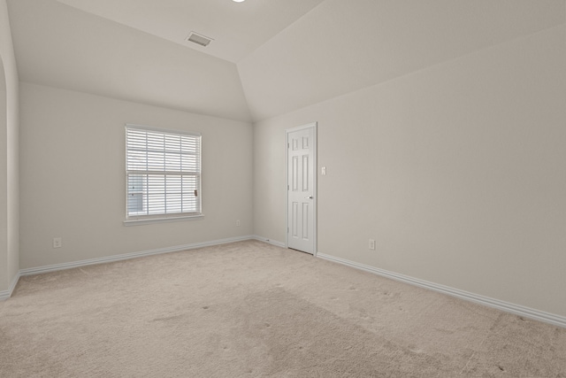 unfurnished room with light colored carpet and lofted ceiling