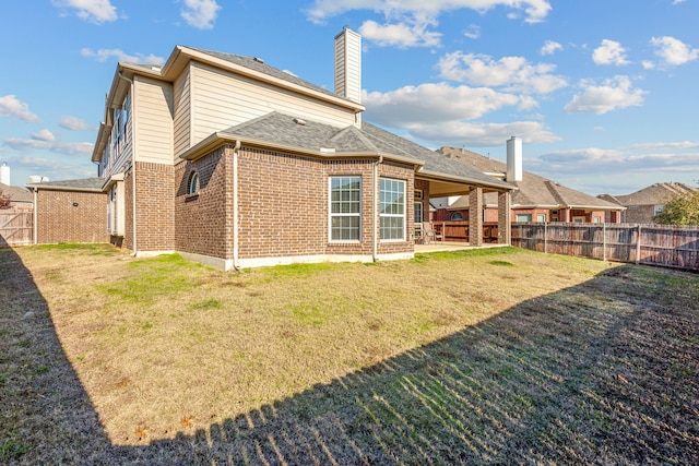 rear view of house featuring a lawn and a patio