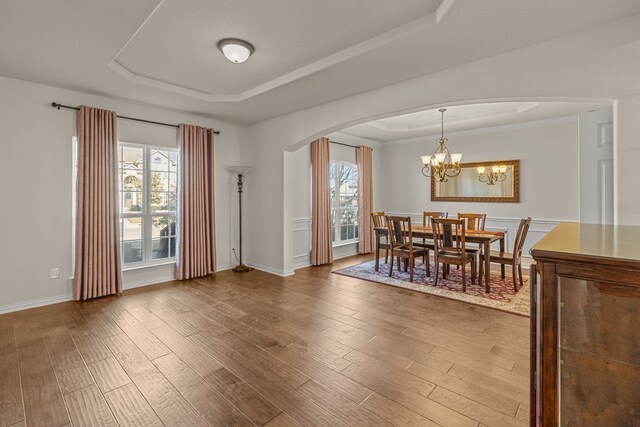 dining room featuring hardwood / wood-style floors, a notable chandelier, a raised ceiling, and crown molding