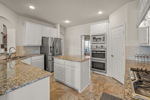 kitchen with appliances with stainless steel finishes, a center island, white cabinetry, and sink