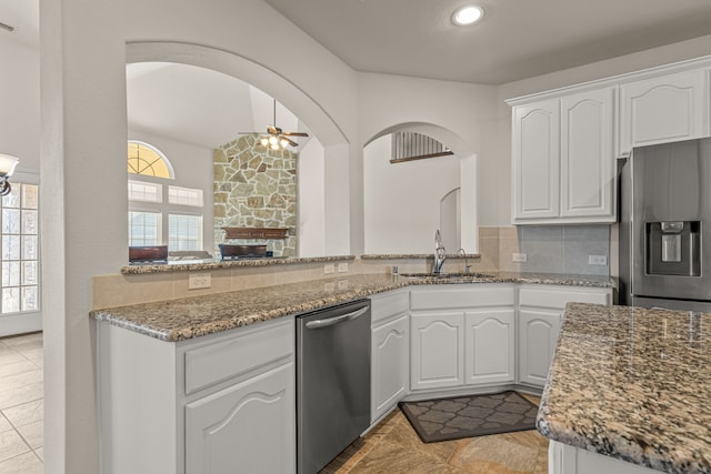 kitchen with appliances with stainless steel finishes, backsplash, sink, dark stone countertops, and white cabinets