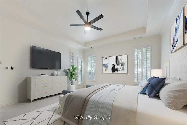 carpeted bedroom with a tray ceiling, multiple windows, and ceiling fan