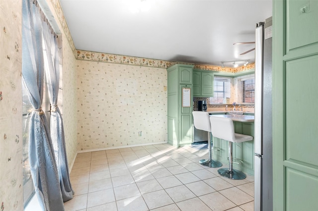 interior space featuring a kitchen breakfast bar, green cabinetry, and light tile patterned flooring