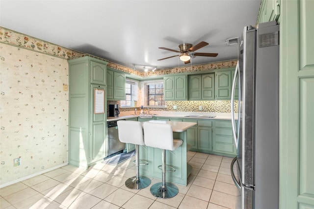 kitchen featuring a center island, stainless steel appliances, a breakfast bar, light tile patterned floors, and green cabinetry