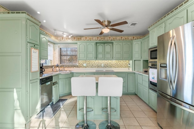 kitchen with light tile patterned floors, stainless steel appliances, ceiling fan, and green cabinets