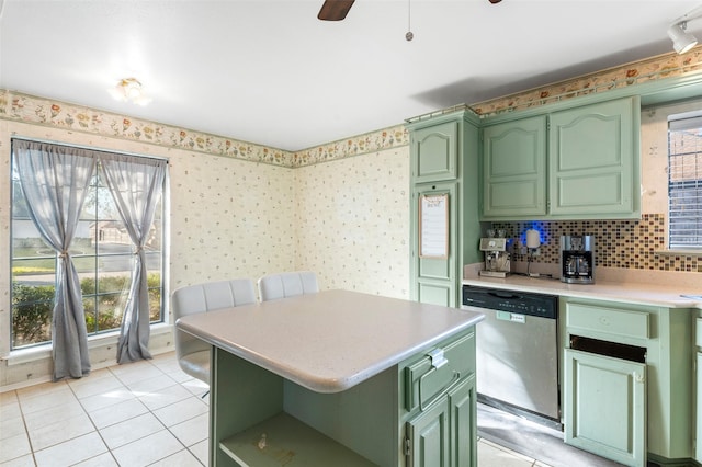 kitchen featuring tasteful backsplash, stainless steel dishwasher, a center island, green cabinets, and light tile patterned flooring