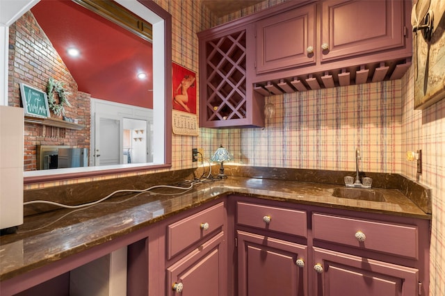 kitchen with dark stone countertops, sink, and vaulted ceiling