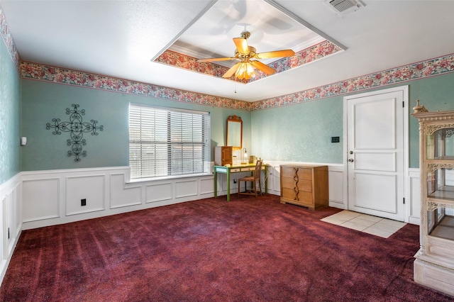 unfurnished office with carpet, a raised ceiling, and ceiling fan