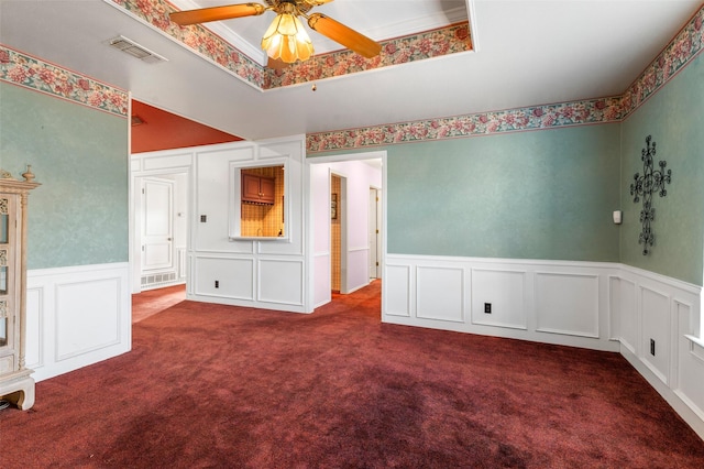 unfurnished room with dark colored carpet, ceiling fan, and crown molding