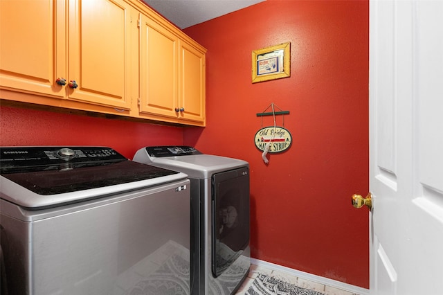 washroom with cabinets, light tile patterned floors, and washing machine and clothes dryer