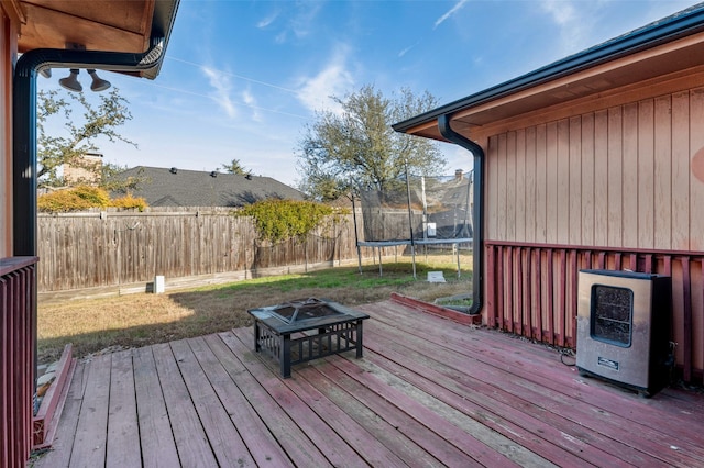 deck featuring heating unit, a fire pit, and a trampoline