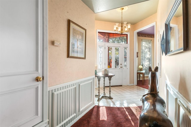 entrance foyer with light tile patterned floors and an inviting chandelier