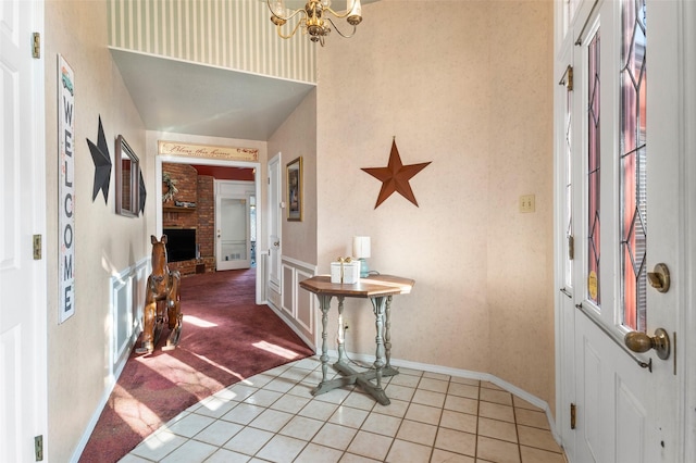 tiled foyer entrance featuring a fireplace and a chandelier