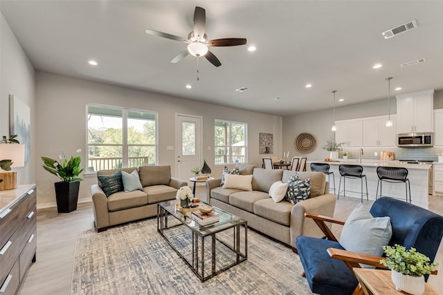 living room featuring ceiling fan and light hardwood / wood-style flooring