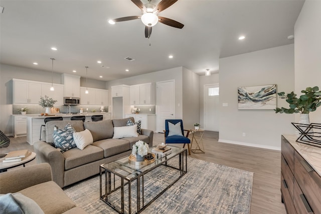 living room with light hardwood / wood-style flooring and ceiling fan