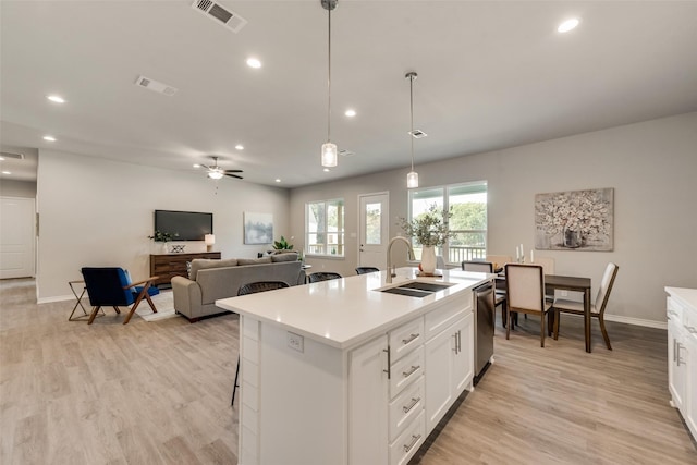 kitchen featuring ceiling fan, a kitchen island with sink, sink, pendant lighting, and white cabinetry