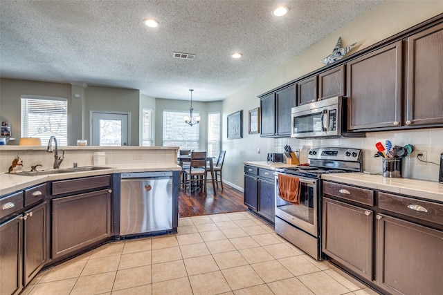 kitchen featuring pendant lighting, dark brown cabinetry, and stainless steel appliances