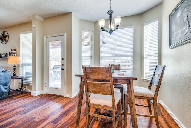 dining space featuring dark hardwood / wood-style flooring, a textured ceiling, and an inviting chandelier