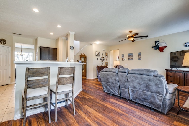 living room with a textured ceiling, ceiling fan with notable chandelier, and dark hardwood / wood-style floors