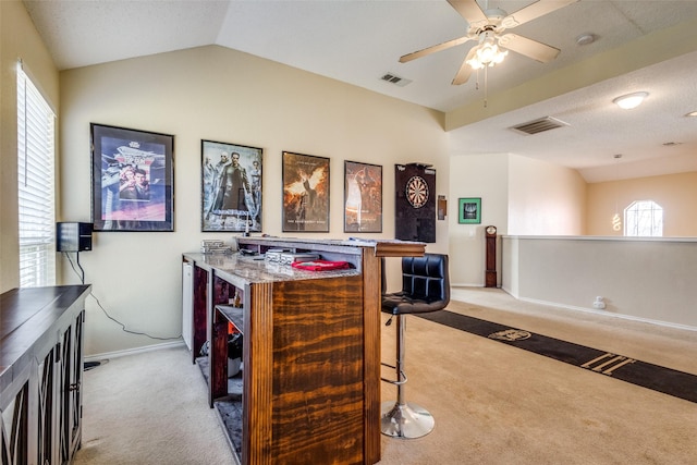 bar featuring ceiling fan, light stone countertops, light carpet, and vaulted ceiling