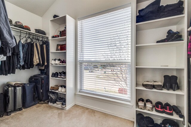 walk in closet with light colored carpet and lofted ceiling